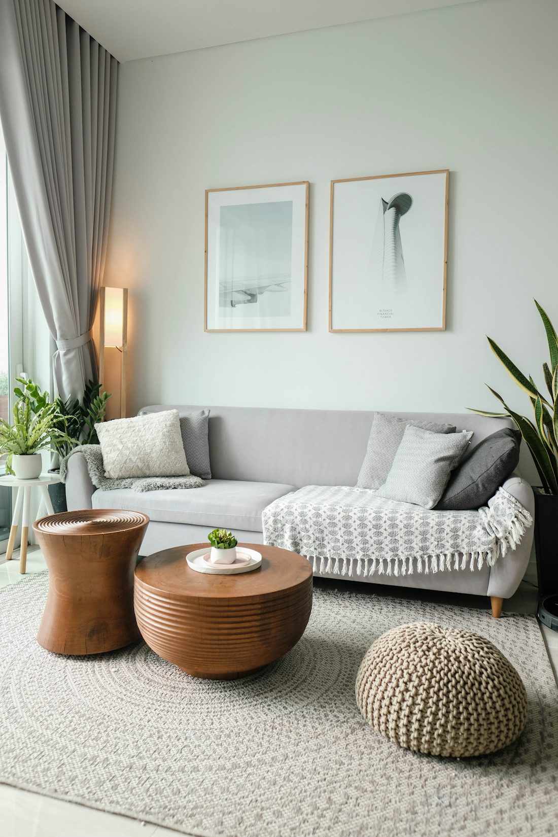 Heller Praxisraum mit hellgrauem Sofa, Holztisch und Pflanzen am Fenster